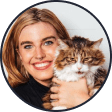 A profile picture of the influencer @itsthecwolf. She smiles at the camera and holds an orange and white cat next to her face.
